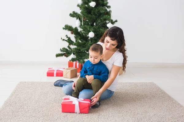 Boże Narodzenie, samotny rodzic i koncepcja święta - Cute little boy gospodarstwa Boże Narodzenie prezent dla matki w domu. — Zdjęcie stockowe