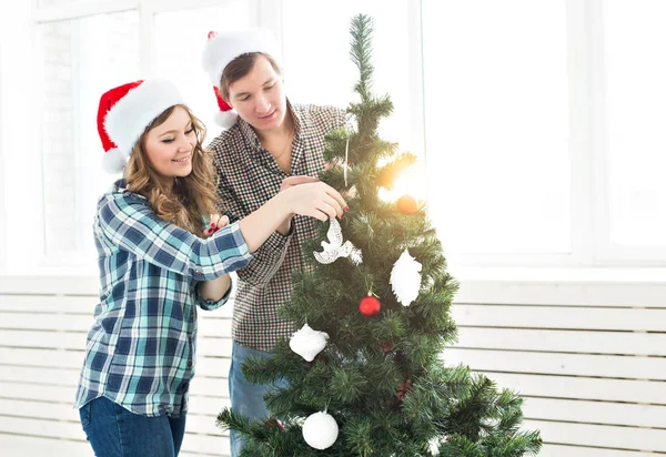 Famiglia, x-mas, vacanze invernali e concetto di persone - felice giovane coppia decorazione albero di Natale a casa — Foto Stock