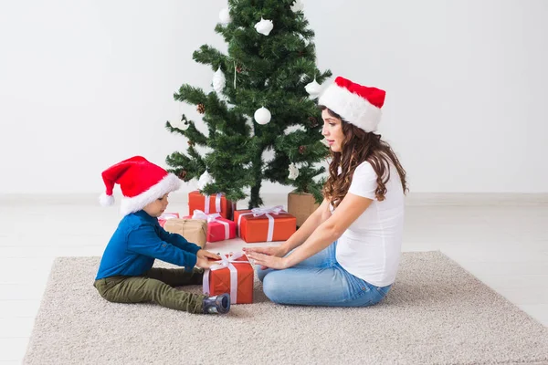 Boże Narodzenie, samotny rodzic i koncepcja święta - Cute little boy gospodarstwa Boże Narodzenie prezent dla matki w domu. — Zdjęcie stockowe