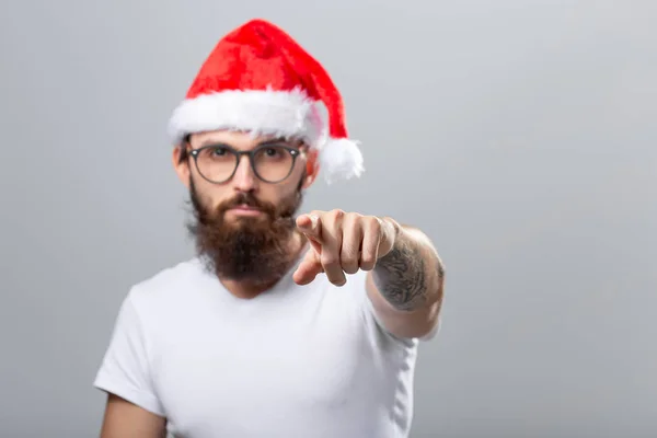 Holidays and people concept - Portret van een knappe brutale man met kerstmuts. Over grijze achtergrond. — Stockfoto