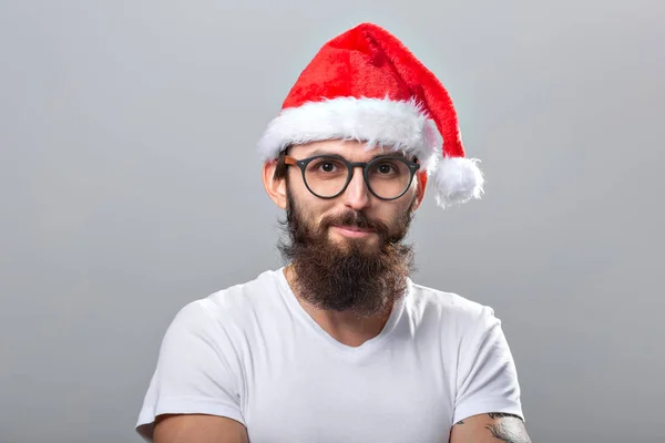 Concepto de vacaciones y personas - Retrato de un hombre guapo y brutal en sombrero de Navidad. Sobre fondo gris . — Foto de Stock