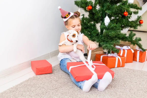 Weihnachts-, Haustier- und Urlaubskonzept - Kind mit Weihnachtsmütze und Jack Russell Terrier Welpe — Stockfoto