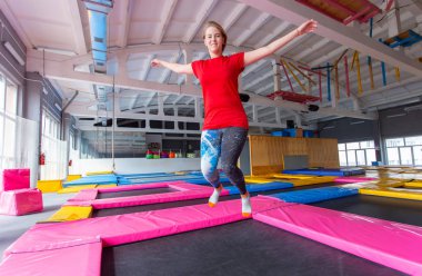 Fitness, eğlence, eğlence ve spor aktivite konsepti - Genç mutlu kadın kapalı bir trambolin üzerinde atlama
