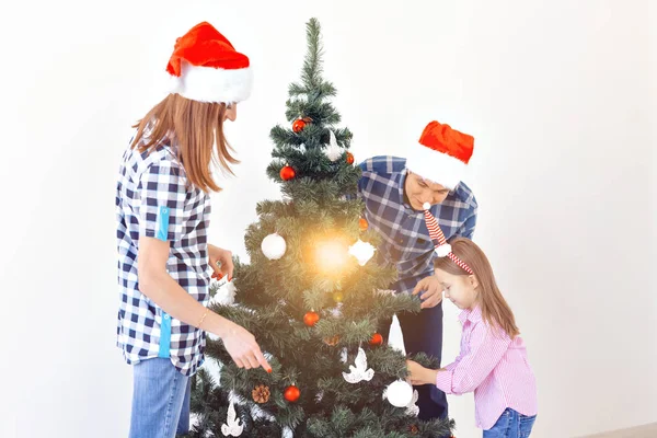 Holidays, x-mas and celebrating concept - Happy family decorating Christmas tree in holiday on white background — Stock Photo, Image