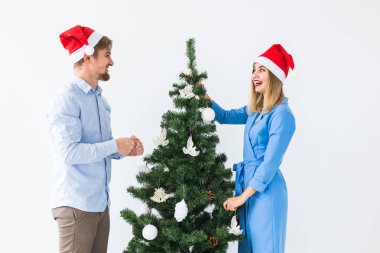 Tatiller ve festival konsepti Noel Baba şapkalı genç bir çift Noel ağacını süslüyor.