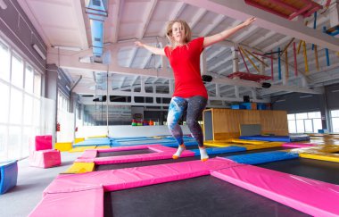 Fitness, eğlence, eğlence ve spor aktivite konsepti - Genç mutlu kadın kapalı bir trambolin üzerinde atlama