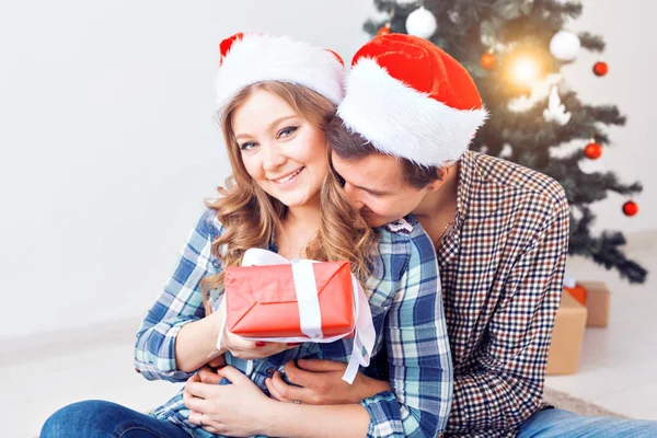 Család, x-mas, téli ünnepek és emberek koncepció - boldog pár átölelve otthon a karácsonyfa közelében — Stock Fotó