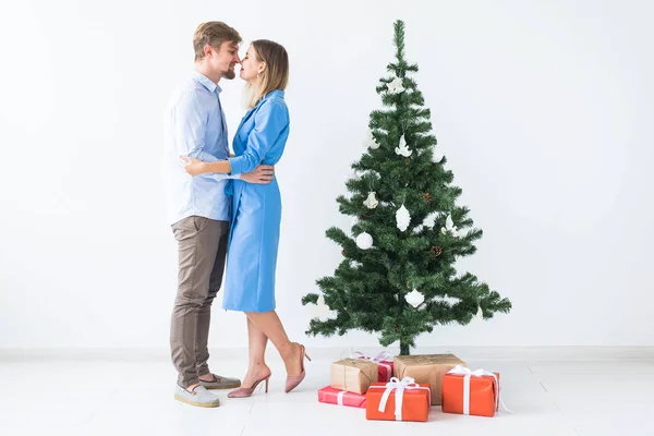 Vacanze e concetto di festa - Giovane coppia felice vicino a un albero di Natale su sfondo bianco — Foto Stock