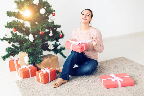 Christmas, x-mas, winter, happiness concept - girl opens a gift against the background of the Christmas tree. Happy young woman celebrating Christmas — Φωτογραφία Αρχείου