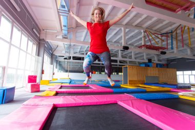 Fitness, eğlence, eğlence ve spor aktivite konsepti - Genç mutlu kadın kapalı bir trambolin üzerinde atlama