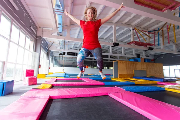 Fitness, eğlence, eğlence ve spor aktivite konsepti - Genç mutlu kadın kapalı bir trambolin üzerinde atlama