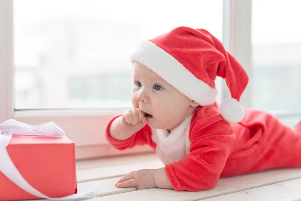Hermoso bebé celebra la Navidad. Vacaciones de Año Nuevo. Bebé en un disfraz de Navidad y en sombrero de santa —  Fotos de Stock