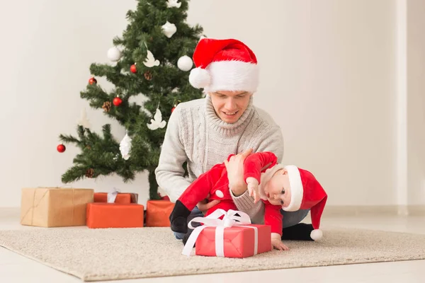 Otec s jeho chlapeček nosí Santa klobouky slaví Vánoce. — Stock fotografie
