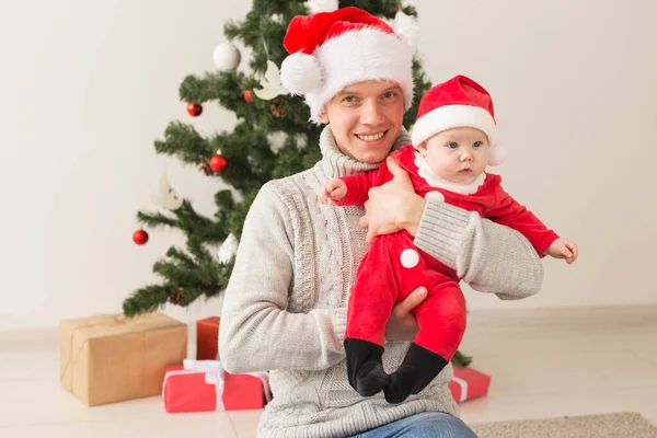 Vader met zijn babyjongen dragen van Santa hoeden we vieren kerst. — Stockfoto