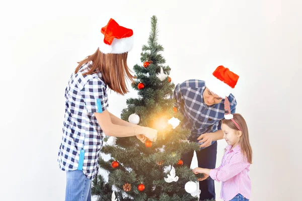 Holidays, x-mas and celebrating concept - Happy family decorating Christmas tree in holiday on white background — Stock Photo, Image