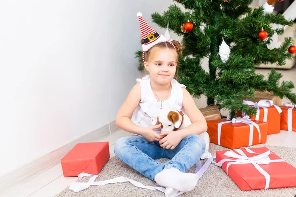 Weihnachts-, Haustier- und Urlaubskonzept - Kind mit Weihnachtsmütze und Jack Russell Terrier Welpe — Stockfoto