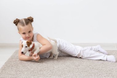 Çocukluk, Evcil hayvan ve köpekler kavramı - küçük çocuk kız köpek yavrusu ile katta poz