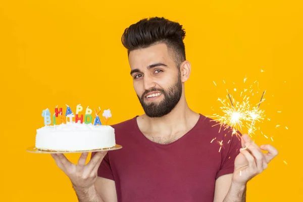 Portré egy vicces pozitív fickó, aki gratuláló házi torta a kezében egy sárga háttér. Koncepció és szórakozás és ünneplés. — Stock Fotó