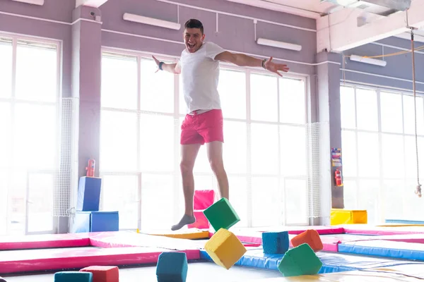 Koncepcja aktywności fizycznej, zabawy, wypoczynku i sportu-przystojny szczęśliwy człowiek skoki na trampolinie w pomieszczeniu — Zdjęcie stockowe