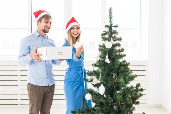 Férias e conceito festivo - Casal jovem da família que decora a árvore de Natal — Fotografia de Stock