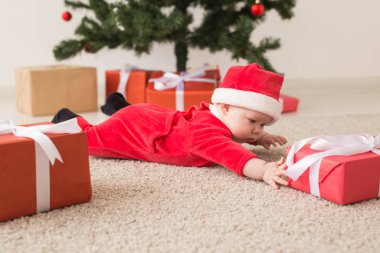 Noel Baba kostümü giyen tatlı bir bebek Noel ağacının üzerinde sürünüyor. Tatil sezonu.