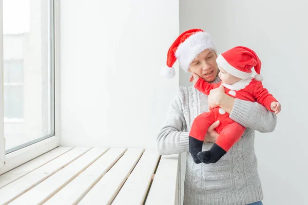 Ojcostwo i święto koncepcja - Ojciec ze swoim małym chłopcem na sobie Santa kapelusze świętowania Bożego Narodzenia — Zdjęcie stockowe