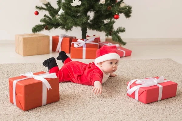 Menina bonito vestindo terno de Papai Noel rastejando no chão sobre a árvore de Natal. Temporada de férias . — Fotografia de Stock