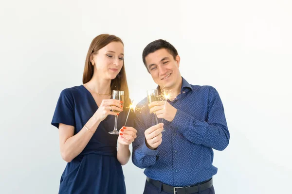 Hombre y mujer celebrando la fiesta de Navidad o Año Nuevo con luces de Bengala y copas de champán sobre fondo blanco . — Foto de Stock