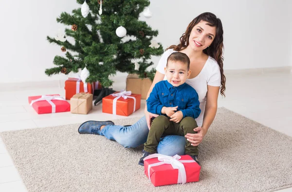 Navidad, padre soltero y el concepto de vacaciones - Lindo niño sosteniendo regalo de Navidad para su madre en el hogar . — Foto de Stock