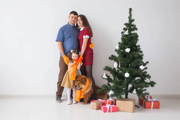 Mascotas, vacaciones y concepto festivo - Familia con perro están de pie cerca del árbol de Navidad . — Foto de Stock