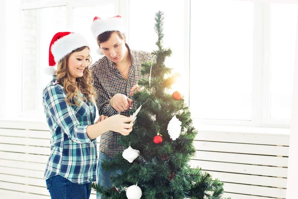 Família, x-mas, férias de inverno e conceito de pessoas - feliz jovem casal decoração árvore de Natal em casa — Fotografia de Stock