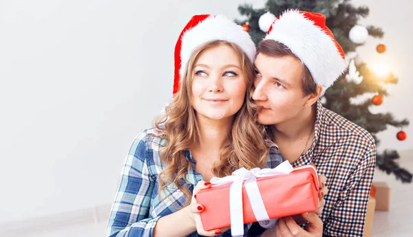Famiglia, x-mas, vacanze invernali e concetto di persone - coppia felice che si abbraccia vicino all'albero di Natale a casa — Foto Stock
