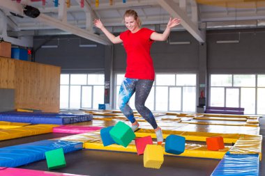 Fitness, eğlence, eğlence ve spor aktivite konsepti - Genç mutlu kadın kapalı bir trambolin üzerinde atlama