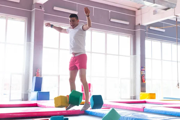 Fitness, diversão, lazer e esporte conceito de atividade - Bonito homem feliz pulando em um trampolim dentro de casa — Fotografia de Stock