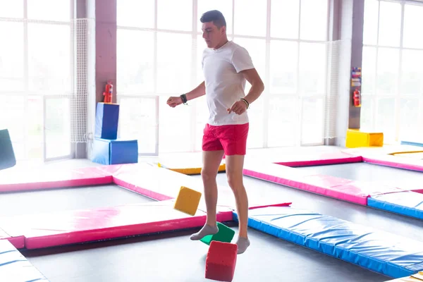 Fitness, diversión, ocio y deporte concepto de actividad - Hombre feliz guapo saltando en un trampolín en el interior — Foto de Stock