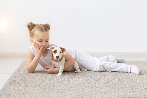 Pessoas, crianças e animais de estimação conceito - menina criança deitada no chão com cachorro bonito Jack Russell Terrier — Fotografia de Stock