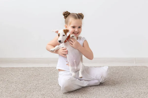 PET, barn och djur koncept-leende barn flicka sitter med valp Jack Russell Terrier — Stockfoto