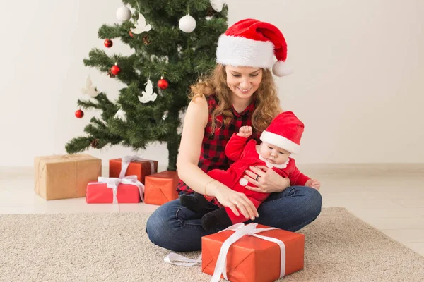 Rodinný, dětský a vánoční koncept - Portrét šťastné matky a roztomilého miminka v obleku Santy — Stock fotografie