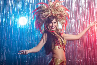 Kabare, dansçı ve tatil konsepti - Koyu arka plan üzerinde parlak renkli karnaval kostümsevimli genç kız