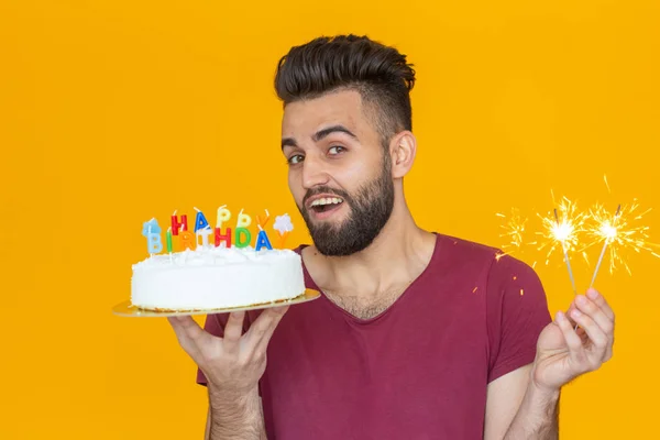 Portret zabawny pozytywny facet trzyma gratulacyjny domowej roboty ciasto w dłoniach na żółtym tle. Koncepcja i zabawa i uroczystość. — Zdjęcie stockowe