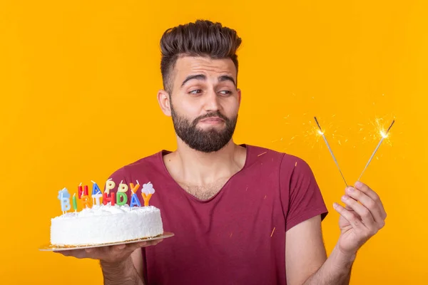 Young male hipster with a beard holding a cake with the inscription happy birthday congratulations on the anniversary and the holiday. Concept of promotions and discounts.
