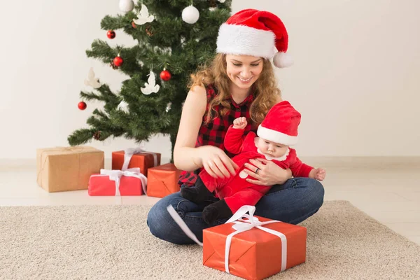 Familia, infancia y concepto de Navidad - Retrato de madre feliz y adorable bebé en traje de Santa — Foto de Stock