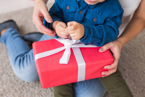 Christmas, single parent and holidays concept - Close-up of cute little boy holding christmas present for his mother at the home.