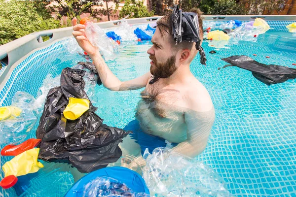 Ecology, plastic trash, environmental emergency and water pollution - shocked man swim in a dirty swimming pool
