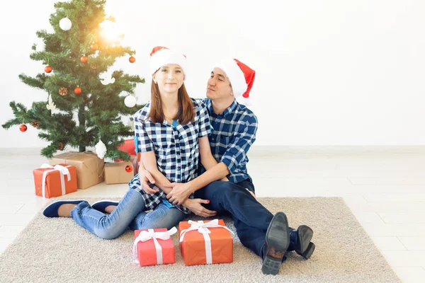 Család, x-mas, téli ünnepek és emberek koncepció - boldog pár átölelve otthon a karácsonyfa közelében — Stock Fotó