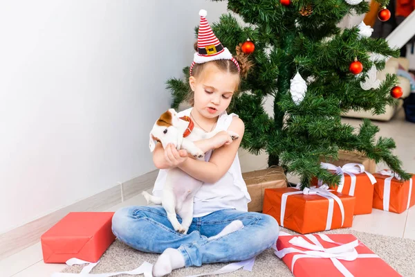 Weihnachts-, Haustier- und Urlaubskonzept - Kind mit Weihnachtsmütze und Jack Russell Terrier Welpe — Stockfoto