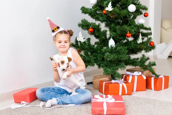 Natale, animali domestici e vacanze concetto - Bambino in cappello di Babbo Natale con un cucciolo jack russell terrier — Foto Stock