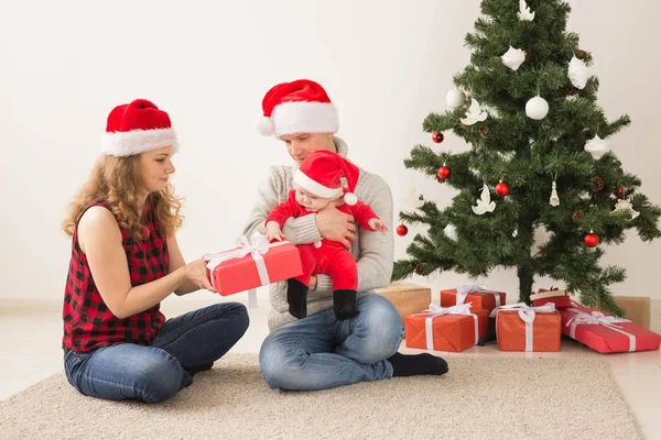 Dovolená, děti a rodinná koncepce - Šťastný pár s miminkem slaví Vánoce společně doma. — Stock fotografie