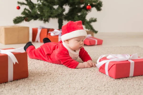 Carina la bambina che indossa la tuta di Babbo Natale strisciando sul pavimento sopra l'albero di Natale. Stagione delle vacanze . — Foto Stock