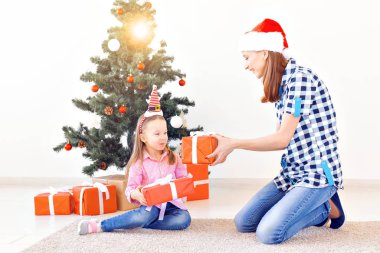 Noel, aile ve tatil konsepti. Evde, oturma odasındaki kanepede şenlikli anne ve kız.